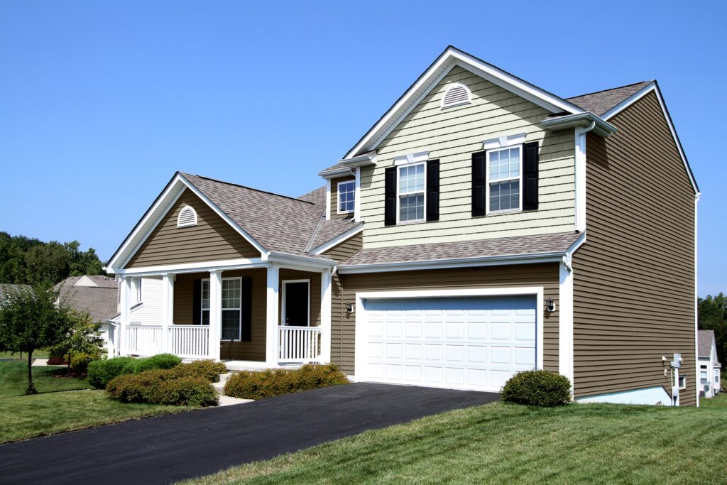 Brown vinyl lap siding paired with cream-colored shake siding on the gables of a suburban home.